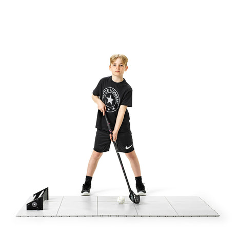 Young floorball player training on snap-together floor tiles